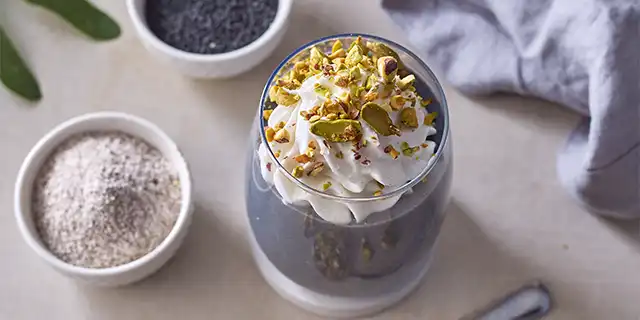 A naturally black latte made with black sesame paste, topped with vegan cream and pistachios