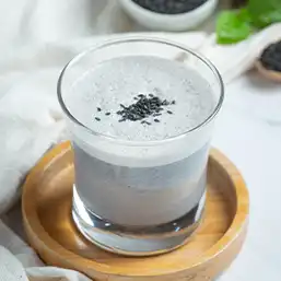 A glass of drinking yogurt with black sesame inclusions