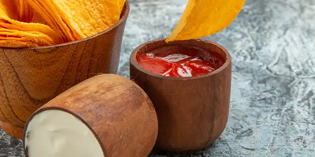 A bowl of well seasoned potato chips next to some creamy dip