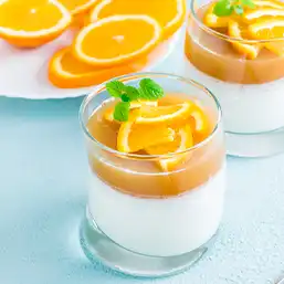 A jar of pudding with orange flavoured layers and topped with fresh cuts of citrus