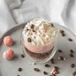 A jar of dessert topped with perfectly swirled whipping cream and sweet toppings