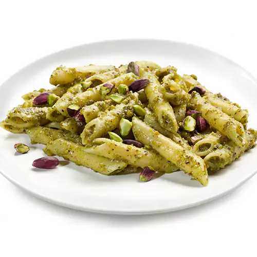 Close up shot of penne pasta with pesto and crushed pistachios sprinkled on top